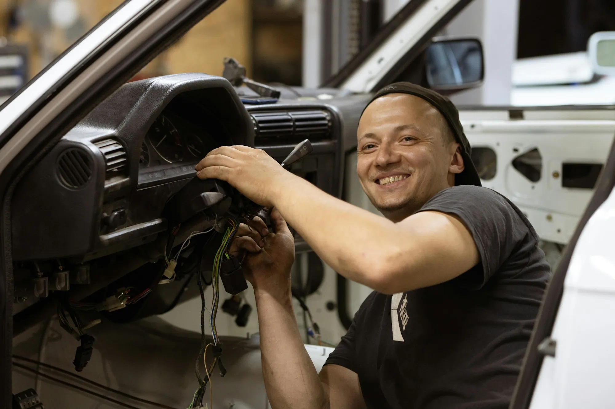Technician smiling while working under a vehicle's dashboard
