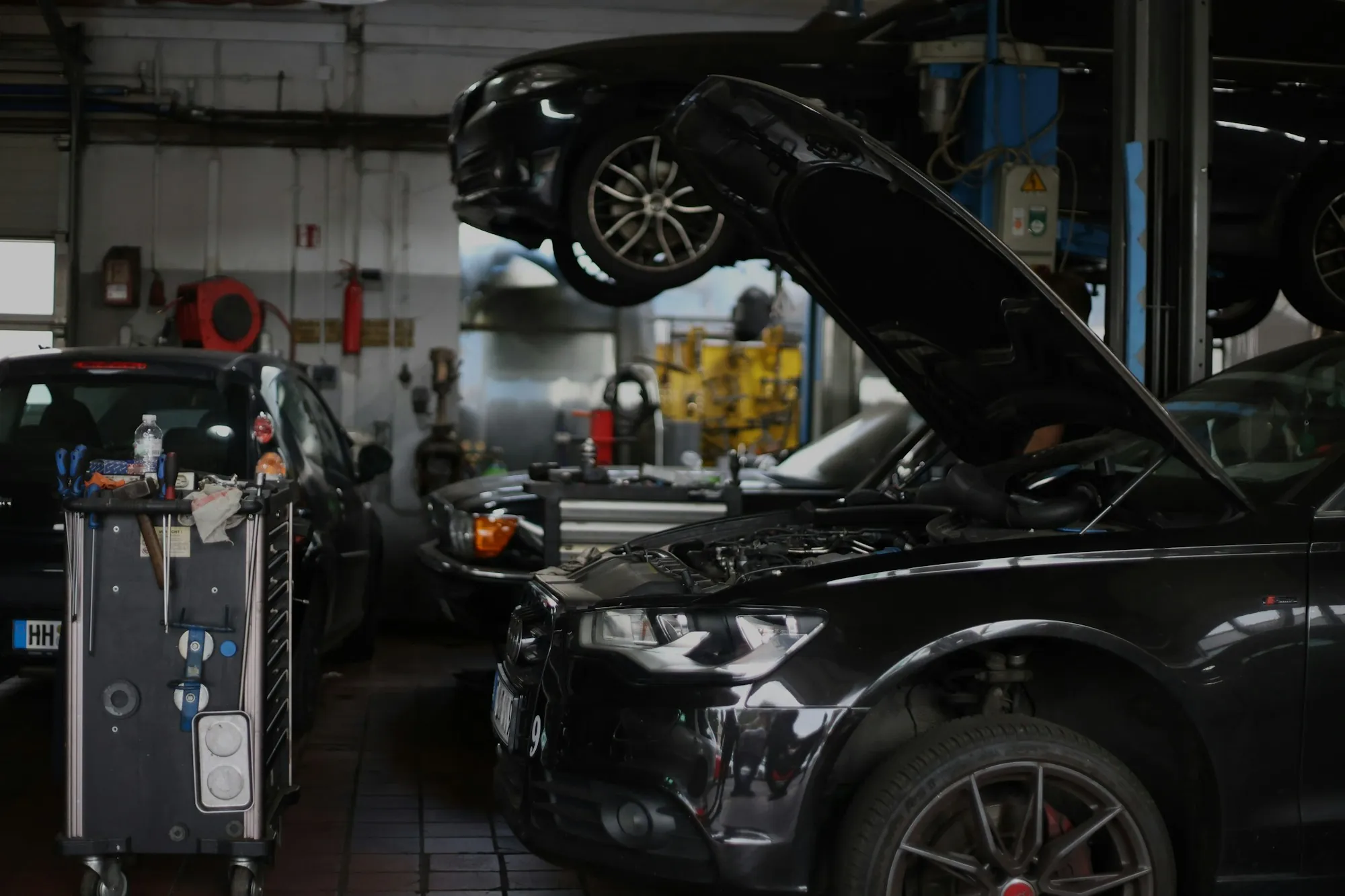 Repair shop with a dark car raised and its hood open
