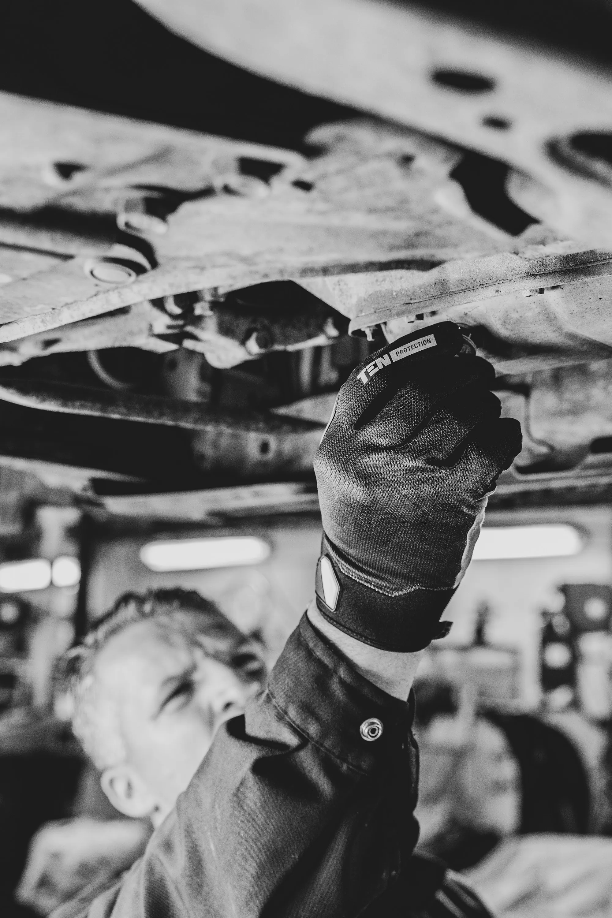 Mechanic in a ventilation mask working beneath a raised vehicle